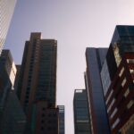 Modern skyscrapers with glass facades reflecting daylight in a bustling cityscape.