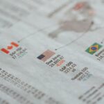 Detailed close-up of a newspaper displaying global financial market statistics and country flags.