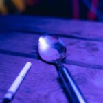 Dramatic depiction of potential drug use with spoon and cigarette in moody lighting.