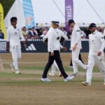 Cricket players and umpire on field during a match in Cheltenham, England.