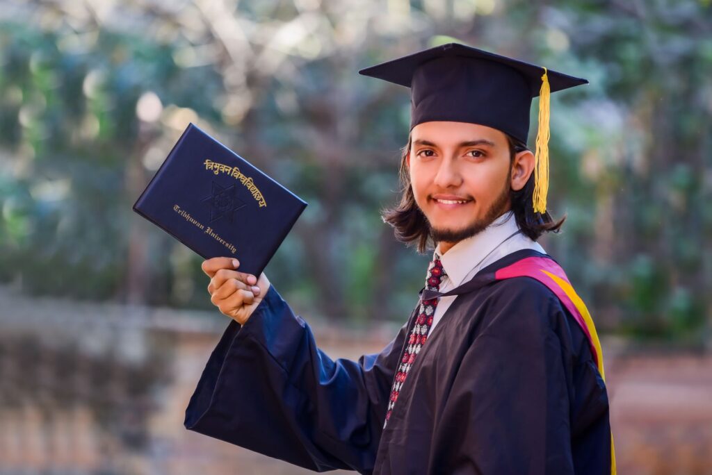 Smiling graduate in cap and gown holds diploma outdoors, celebrating academic achievement.