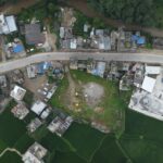 Explore the aerial view of Panauti, Nepal, showcasing green fields, roads, and village homes.