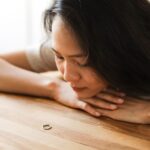 Woman gazing at a wedding ring, contemplating relationship decisions.