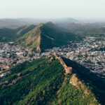 A stunning aerial view of Jaipur city, India, showcasing its historic fortifications and lush mountain ridge.