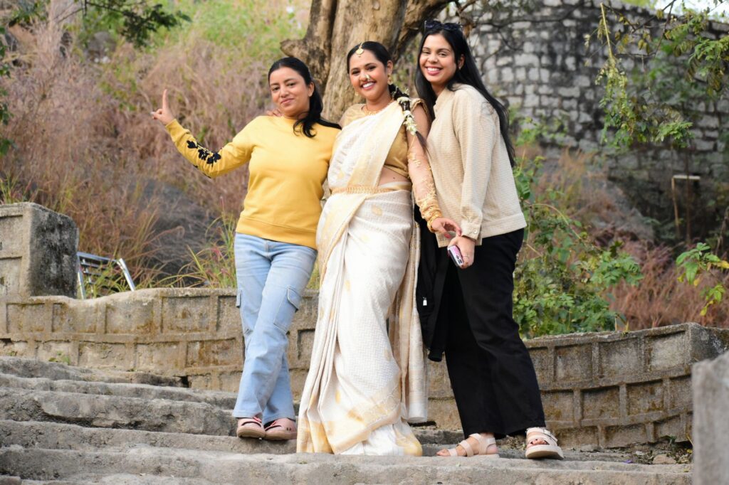 Three smiling women pose outdoors in colorful attire, embodying joy and friendship.