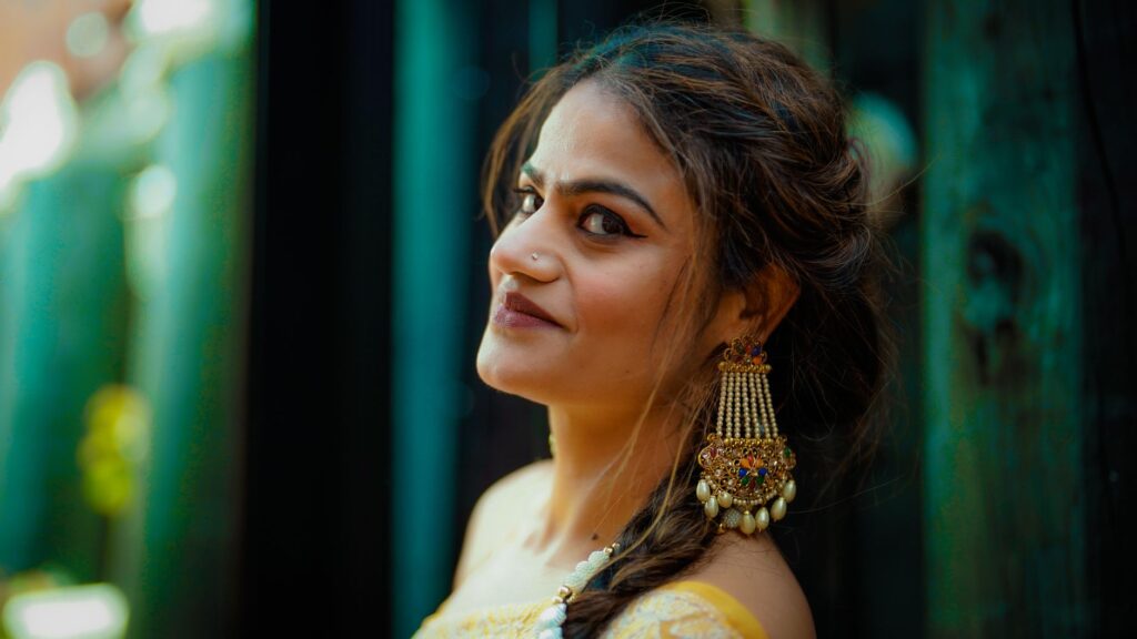 Close-up portrait of a smiling woman wearing traditional jewelry with a blurred background, exuding elegance and charm.