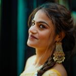 Close-up portrait of a smiling woman wearing traditional jewelry with a blurred background, exuding elegance and charm.