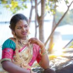 A woman in Chennai wearing a colorful sari and jewelry, smiling outdoors.