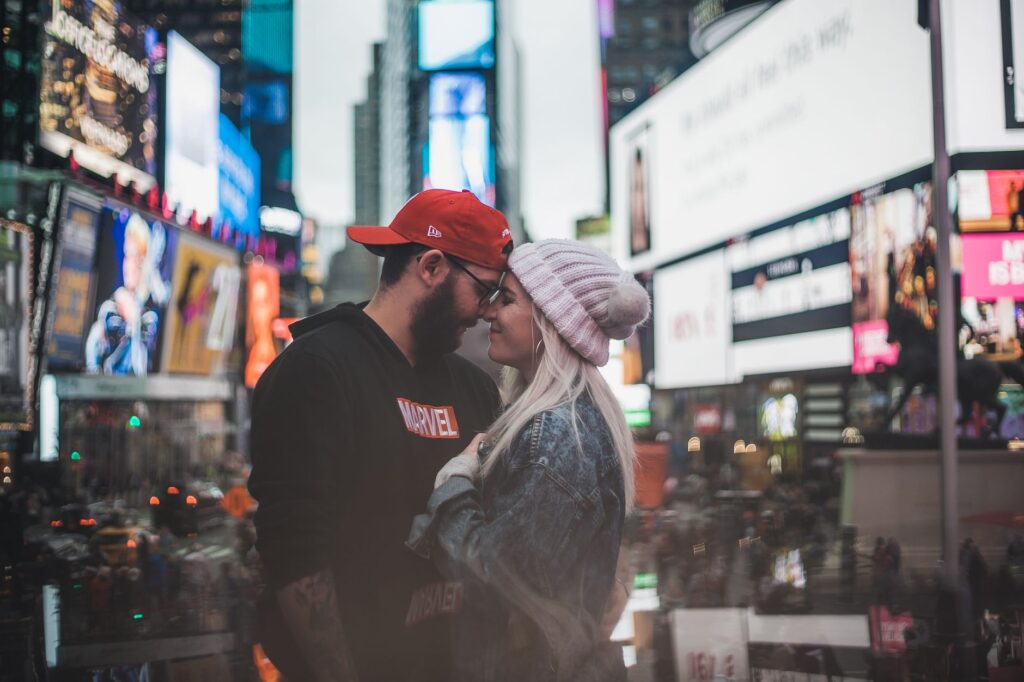A couple shares a tender moment amidst the bright lights of Times Square, New York City.