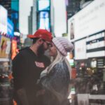 A couple shares a tender moment amidst the bright lights of Times Square, New York City.