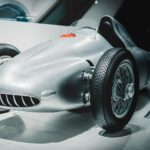 Vintage race car on display in a modern museum setting. Ideal for historical automotive concepts.