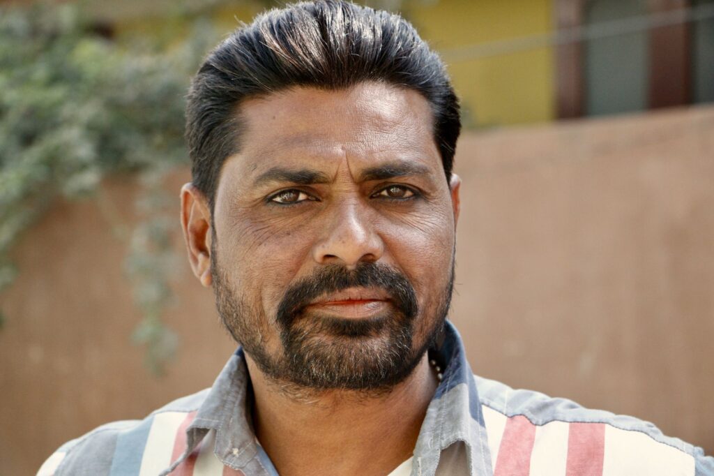 Close-up portrait of a South Asian man outdoors with a contemplative look.