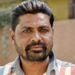 Close-up portrait of a South Asian man outdoors with a contemplative look.