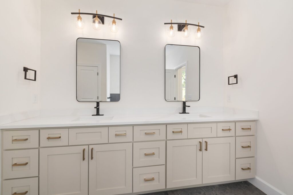 Elegant modern bathroom vanity with two mirrors, white cabinets, and stylish lighting.