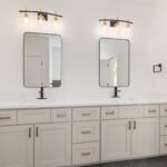 Elegant modern bathroom vanity with two mirrors, white cabinets, and stylish lighting.