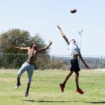 Two men catching a football during an outdoor game in Fort Hood, Texas.
