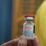 Detailed view of a Moderna COVID-19 vaccine vial held in hand, highlighting immunization efforts.