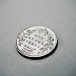 Close-up photograph of a 1907 silver Indian rupee coin with intricate details.