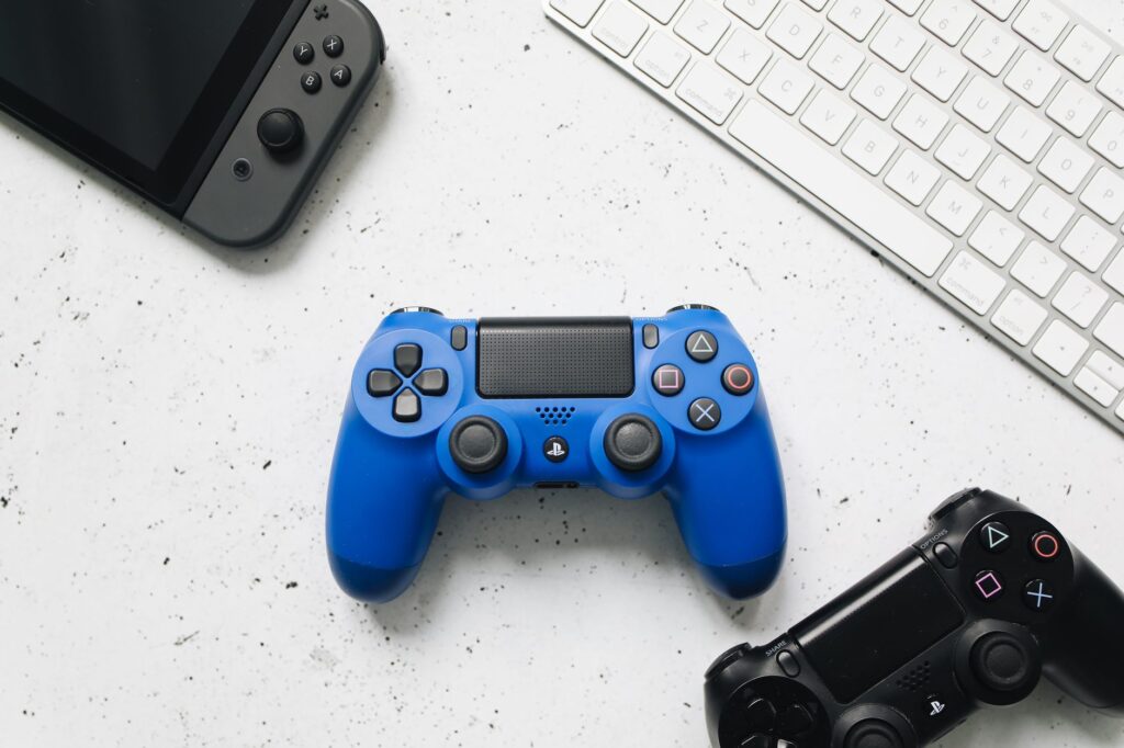 Top view of various gaming controllers and a keyboard on a white surface.