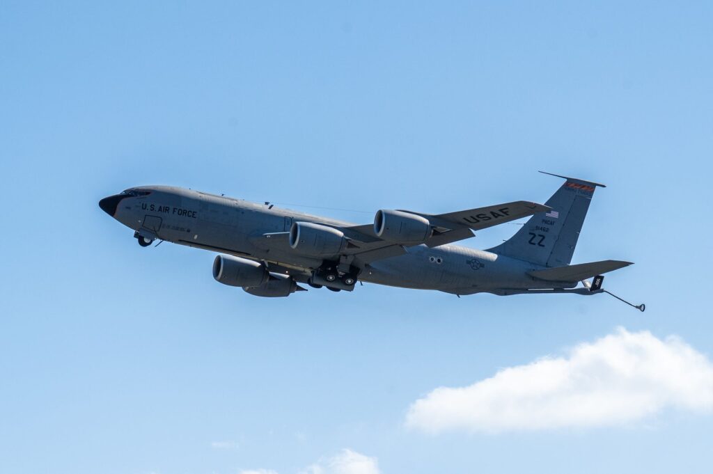 A US Air Force aircraft flying through a clear blue sky on a sunny day.