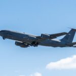 A US Air Force aircraft flying through a clear blue sky on a sunny day.