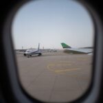 Airplane seen through a window, parked on the airport runway, capturing a travel moment.