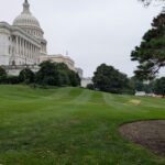 View of the US Capitol with green lawns and overcast skies in Washington DC.