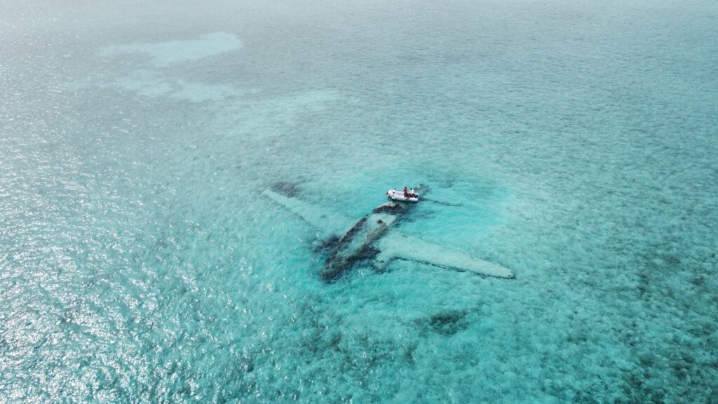 Drone shot of a sunken airplane beneath turquoise water, ideal for travel and adventure themes.