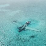 Drone shot of a sunken airplane beneath turquoise water, ideal for travel and adventure themes.
