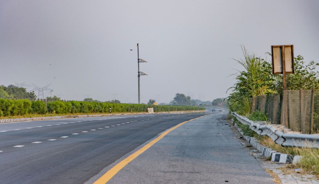 Serene landscape of an empty expressway in Deeg, India with lush greenery.