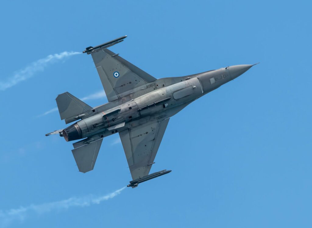 Dynamic shot of a Greek F-16 jet soaring through a clear blue sky, showcasing its sleek design.