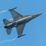 Dynamic shot of a Greek F-16 jet soaring through a clear blue sky, showcasing its sleek design.