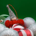 A cheerful elf Christmas ornament surrounded by glittery holiday decorations.