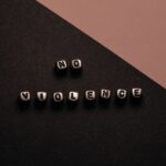 Artistic composition with text cubes spelling 'No Violence' on a two-tone background.