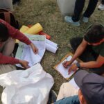 Election officials organizing ballots in an outdoor setting in Nepal, highlighting the electoral process.