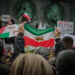 Protest in Stockholm with Iranian flags and social issue slogans.