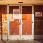 A locked and boarded school entrance with no trespassing signs emphasizing safety rules.