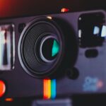 Artistic close-up shot of a vintage instant camera lens with colorful accents.