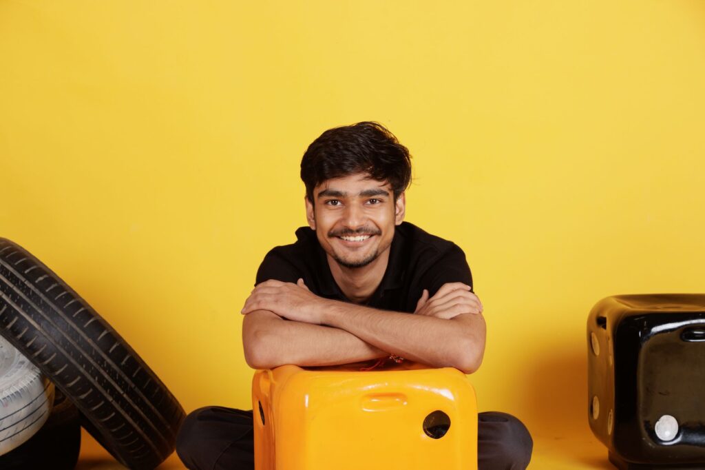 Smiling young man in casual wear posing with colorful props indoors, radiating positivity and joy.