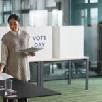 Asian woman preparing voting materials on election day.