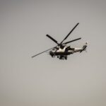 A military attack helicopter flying against a gray sky, showcasing defense technology.