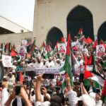 Large Pro-Palestinian demonstration in Dhaka with flags and banners supporting freedom and solidarity.