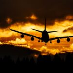Airplane silhouette glides through a dramatic sunset sky, creating a striking aviation scene.