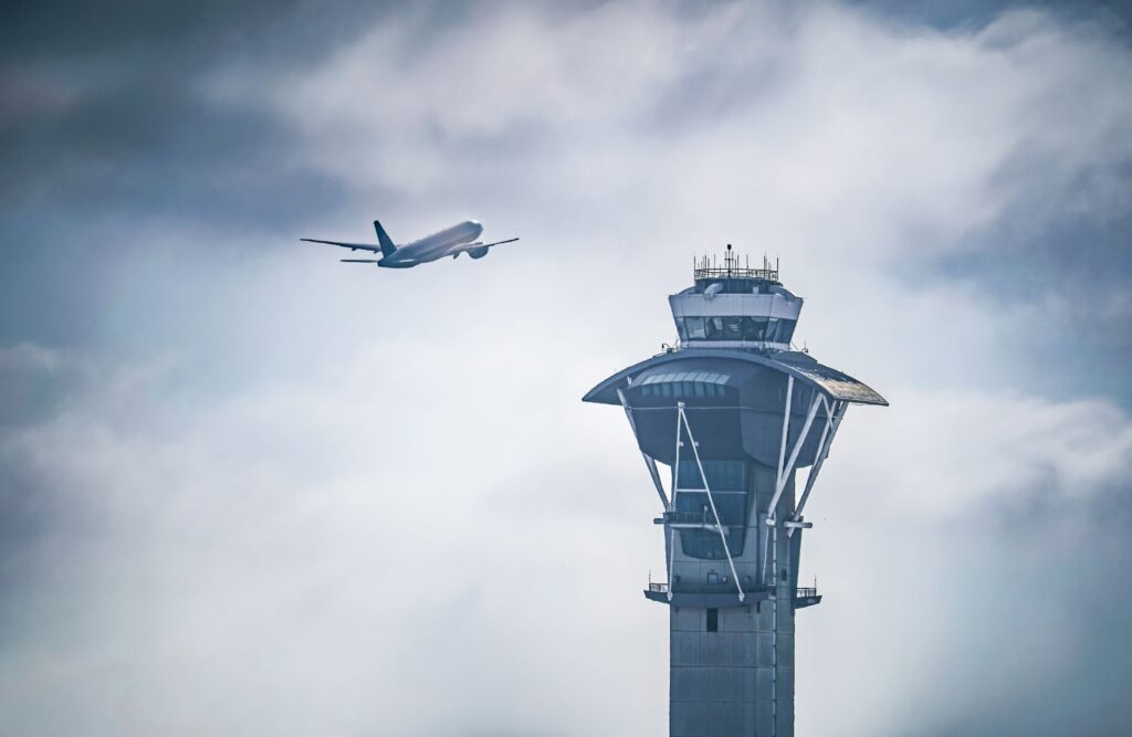 Dramatic shot of an airplane taking off near the iconic LAX control tower in Los Angeles, California.
