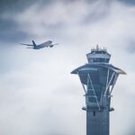 Dramatic shot of an airplane taking off near the iconic LAX control tower in Los Angeles, California.