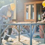Two construction workers using power tools on a sunny day.