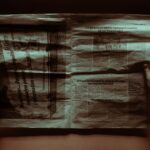 A person reading a retro newspaper at a desk in moody lighting, evoking nostalgia.