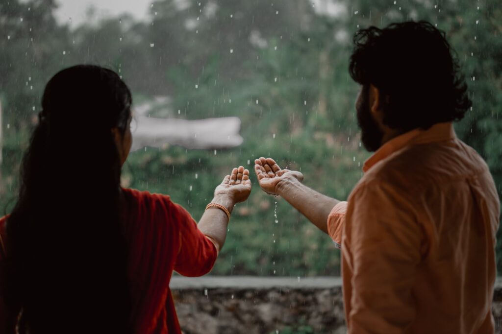 A couple enjoying the rain, capturing a romantic and joyful moment with open hands.