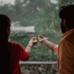 A couple enjoying the rain, capturing a romantic and joyful moment with open hands.