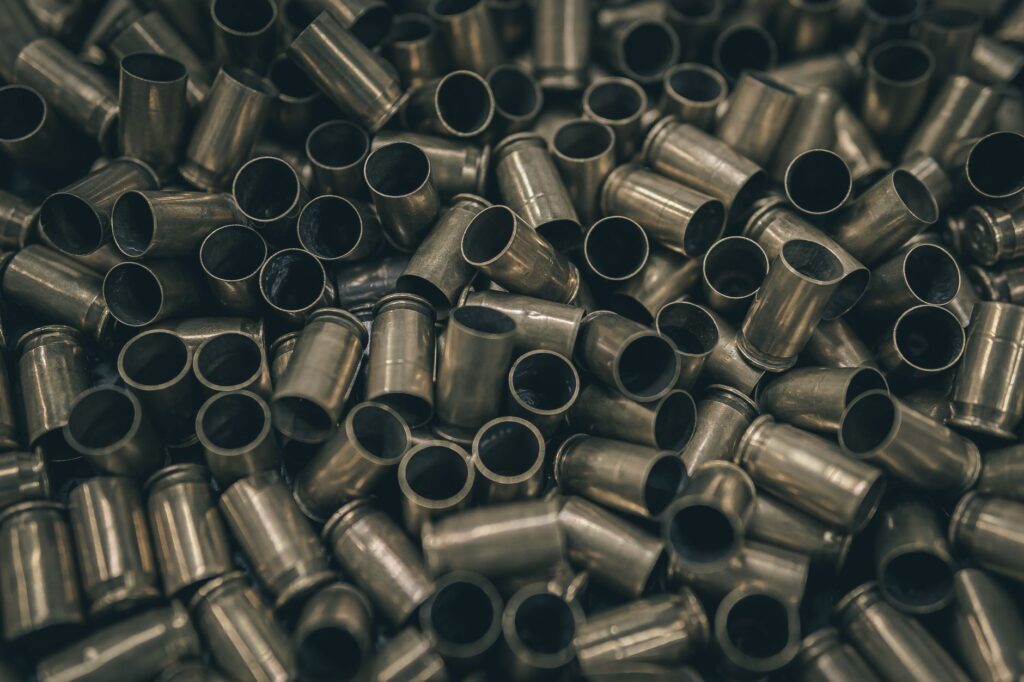 Close-up of a pile of metal bullet casings, emphasizing abundance and metallic texture.
